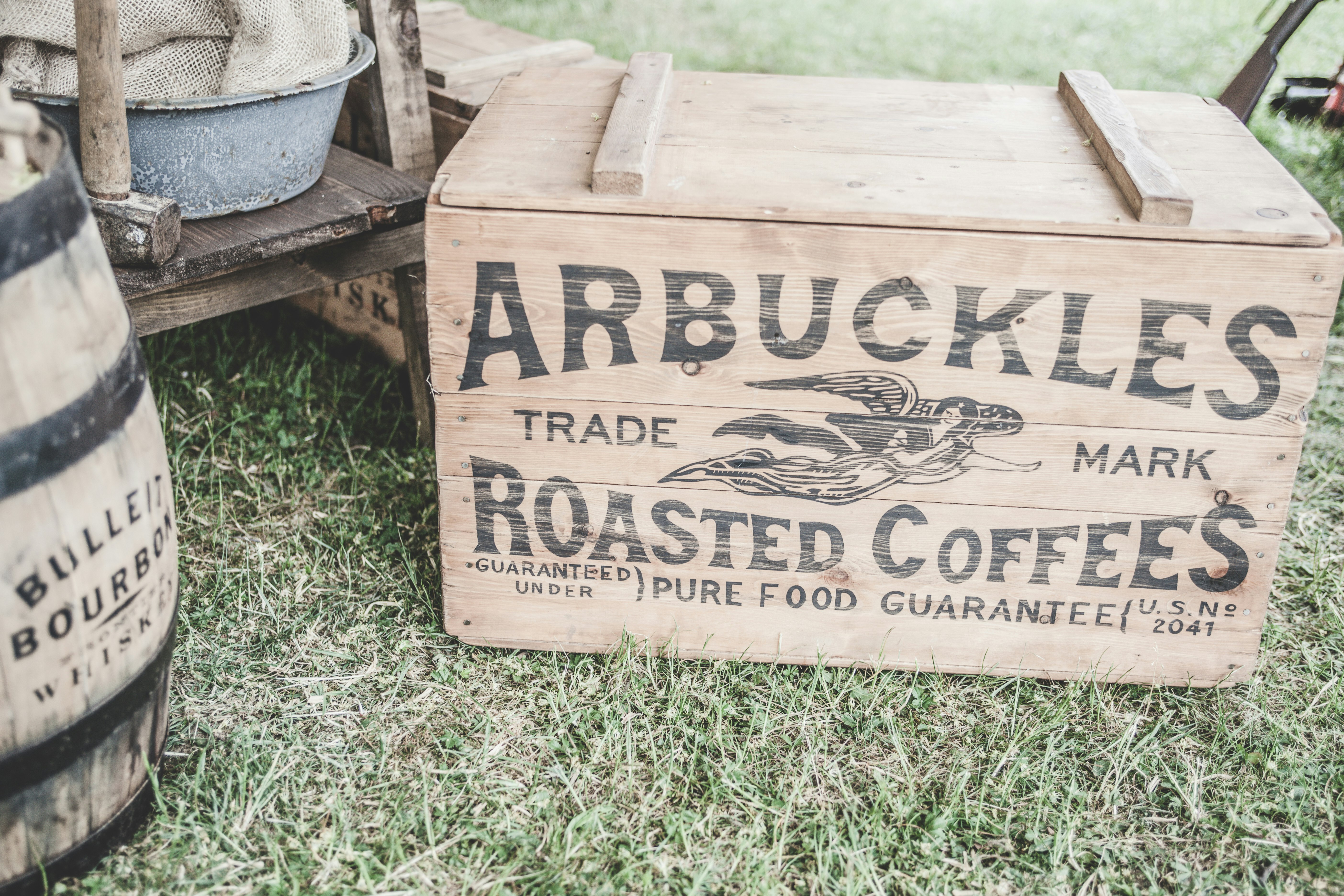 brown wooden storage box beside barrel on grass field